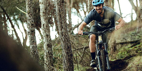 Ein Mensch fährt mit dem Fahrrad durch den Wald