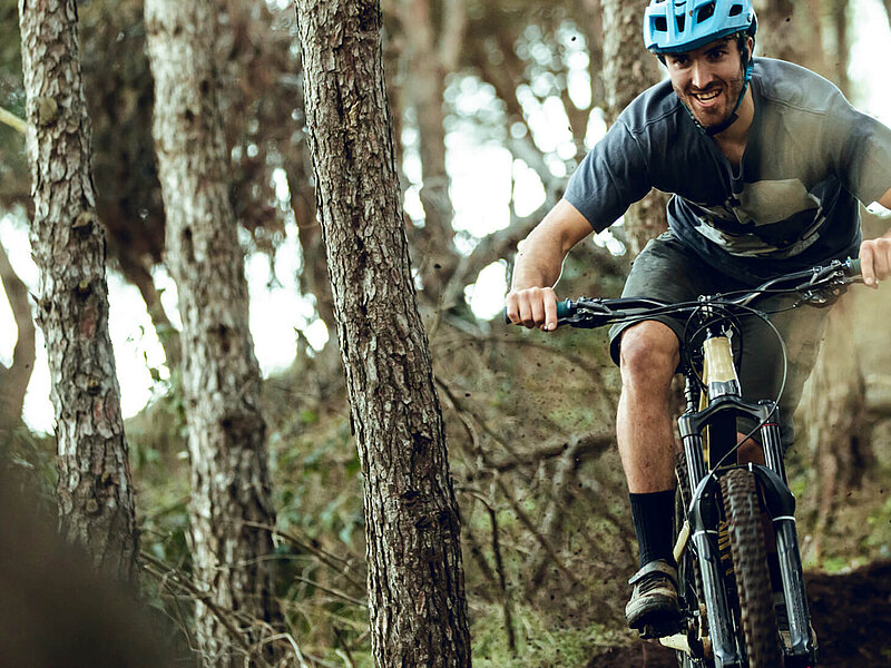 Ein Mensch fährt mit dem Fahrrad durch den Wald