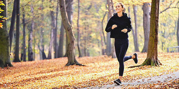 Eine Frau joggt durch einen Wald