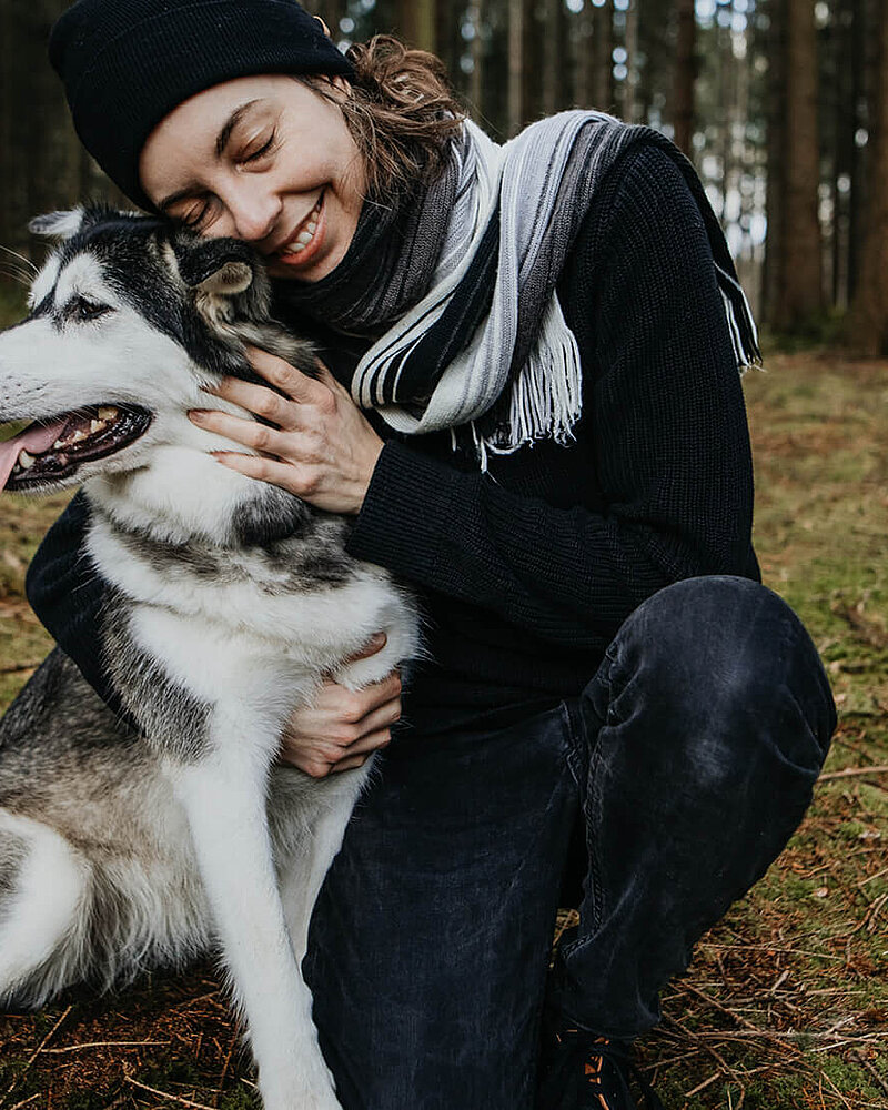 Eine Frau, die im Wald ihren Hund umarmt